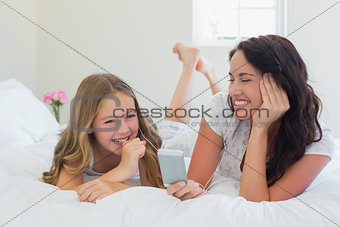 Mother and daughter listening to music in bed