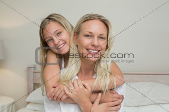 Girl embracing mother from behind in bed