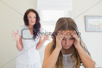 Frustrated girl in bed while mother scolding her