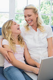 Happy mother and daughter using laptop