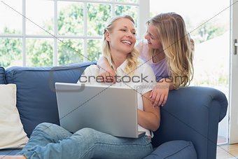Mother and daughter with laptop looking at each other