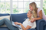 Mother and daughter using laptop in living room