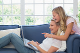 Girl pointing at laptop while mother using it