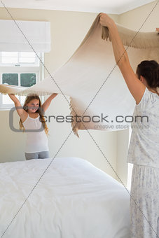Mother and daughter making bed
