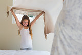Happy little girl making bed with mother