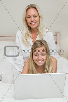 Girl using laptop while mother looking at it