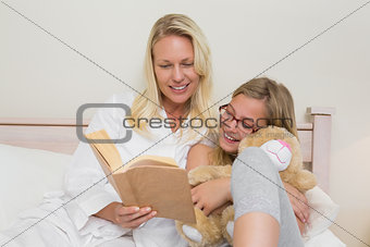 Mother and daughter reading novel in bed