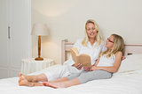 Mother and daughter with story book in bed