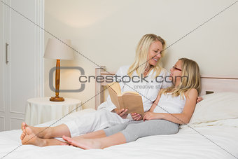 Mother and daughter with story book in bed