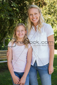 Mother with arm around daughter standing in park