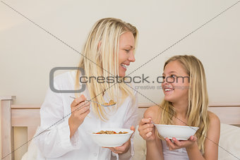 Mother and daughter having cereals in bedroom