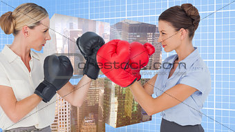 Composite image of businesswomen with boxing gloves fighting
