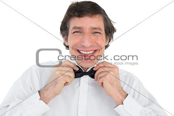 Portrait of groom adjusting bow tie