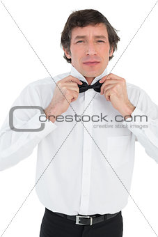 Man adjusting bow tie before wedding