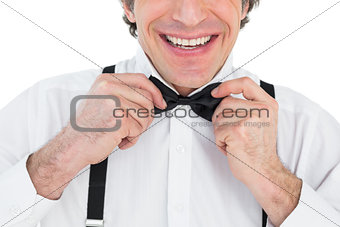 Smiling groom adjusting bow tie