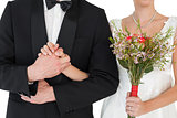 Mid section of bride and groom holding hands