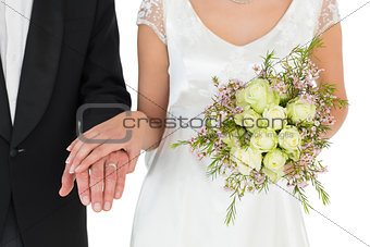 Mid section of bride and groom with rose bouquet