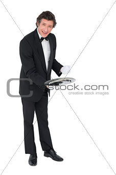 Confident waiter showing empty tray over white background