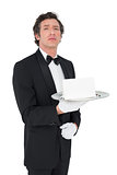 Confident waiter holding tray against white background