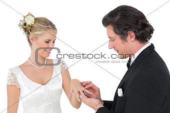 Attractive bride and groom exchanging wedding ring