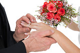 Groom and bride with flowers exchanging wedding ring