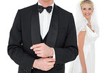 Groom adjusting tuxedo sleeve while bride looking at him