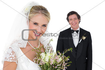 Bride holding bouquet while groom standing in background