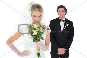 Bride smelling flowers while groom standing in background