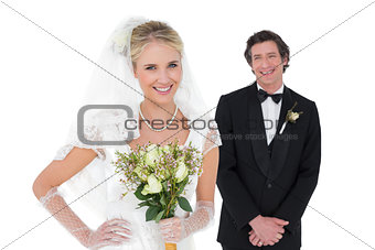 Bride holding flowers while groom standing in background