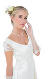 Confident bride touching cheek over white background