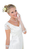 Smiling bride touching cheek over white background