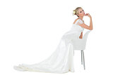 Bride with hand on chin leaning on chair