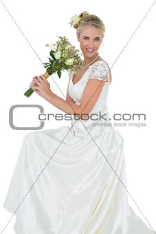 Young bride holding flower bouquet against white background