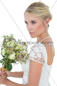 Bride holding flower bouquet while looking away