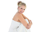 Young bride hugging knees over white background