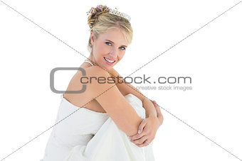 Young bride hugging knees over white background