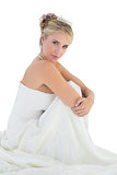 Sensuous bride hugging knees over white background