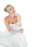 Sensuous bride with hand on chin against white background