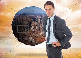 Composite image of serious businessman standing with hands on hips
