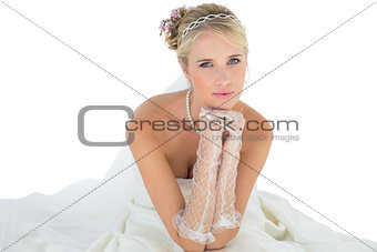 Bride with hand on chin sitting over white background