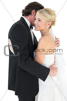 Loving bride and groom embracing over white background