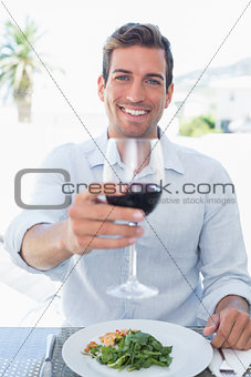 Smiling young man with wine glass having food
