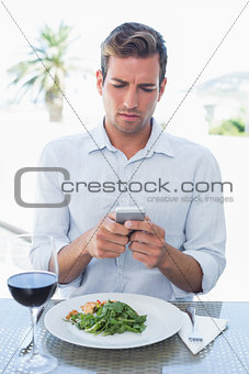 Man text messaging at food table