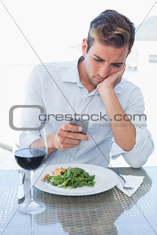 Young man text messaging at food table