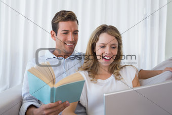 Relaxed loving young couple with book and laptop