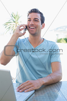 Happy man using laptop and mobile phone
