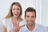Woman showing engagement ring besides man