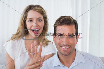 Woman showing engagement ring besides man