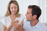 Cheerful woman looking at engagement ring besides man