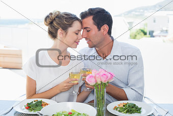 Loving couple toasting wine glasses at lunch table
